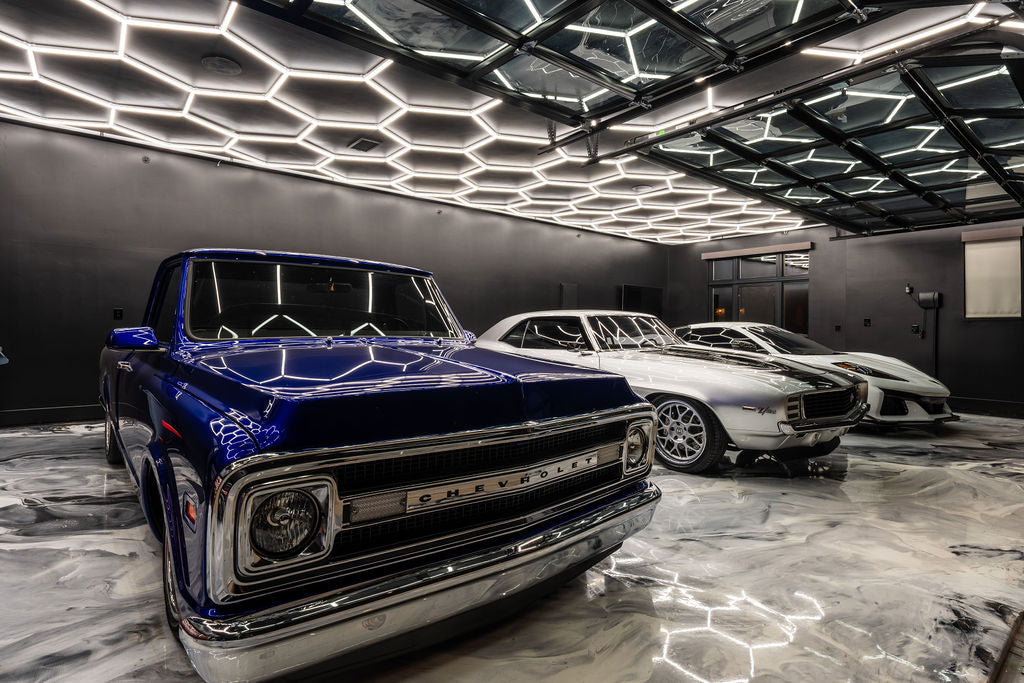 Hexagon garage lighting in modern garage with featuring epoxy floors with classic pickup truck and sports cars