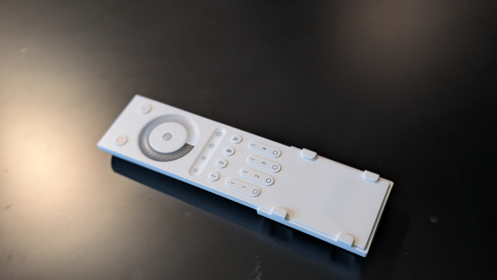White handheld remote with a round dimming wheel, brightness keys and numbered keys 1 to 4
