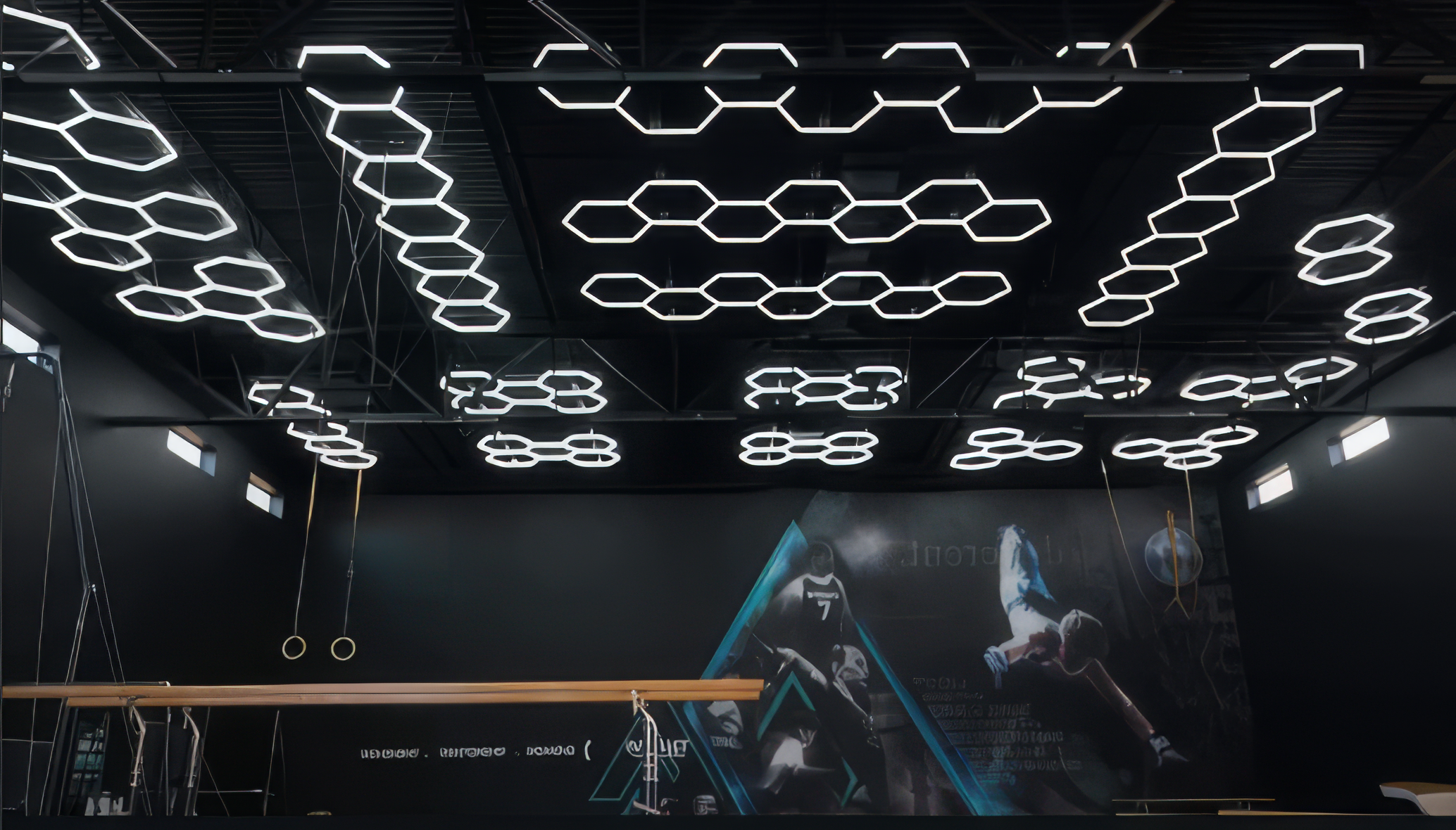 Modern gym with hexagon ceiling lights and a screen displaying futuristic graphics.