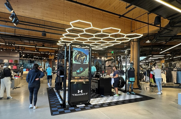 Under Armour store interior with hex lights customers and branded display.