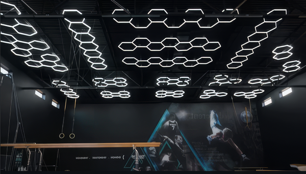 Modern gym with hexagon ceiling lights and a screen displaying futuristic graphics.