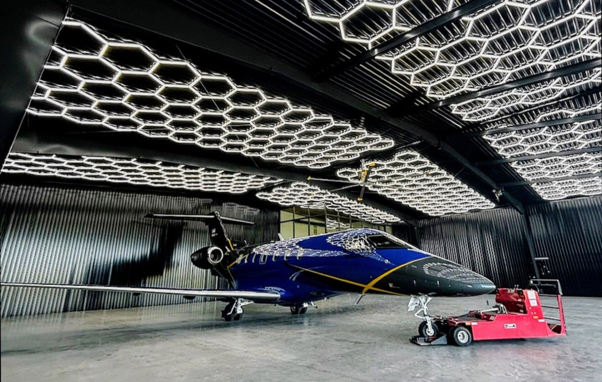 Blue airplane inside a modern hangar with hexagonal ceiling lights