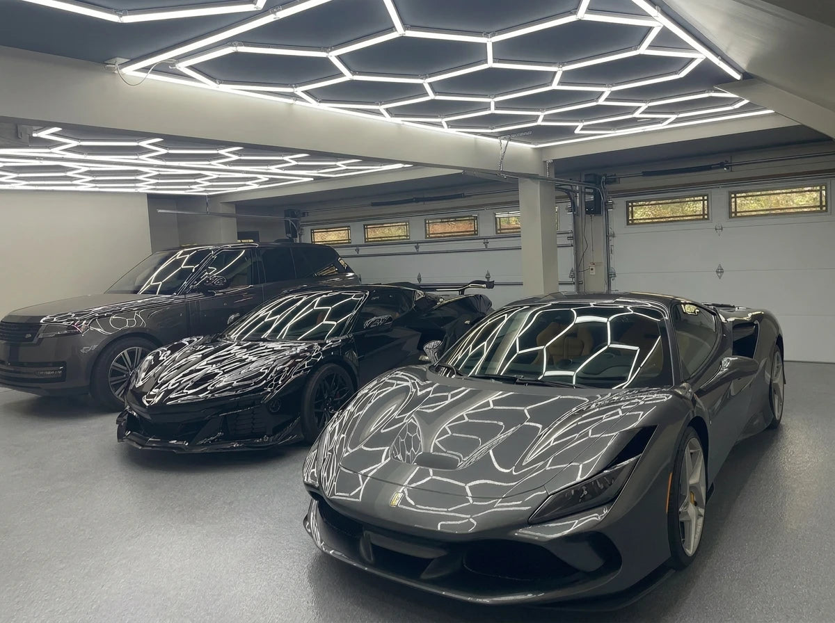 Ferrari sports cars under modern hexagon LED ceiling lighting in a luxury garage