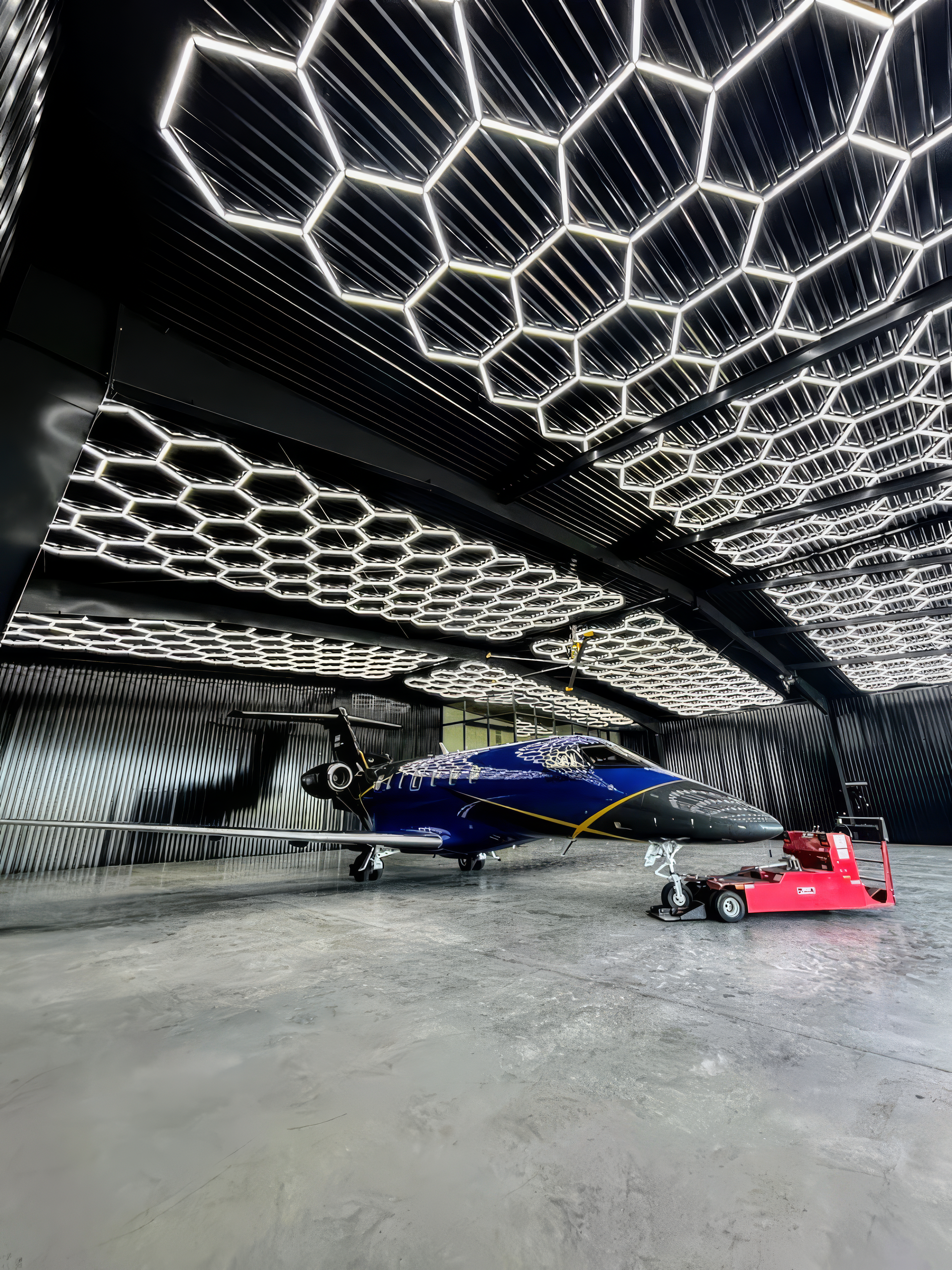 hexagonal ceiling lights inside a modern hangar with Pilatus PC-24, a twin-engine jet_max